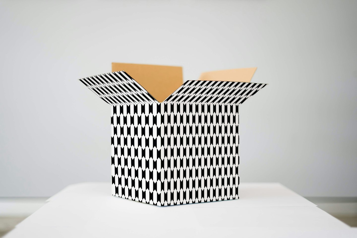 Scatola di cartone aperta con motivo geometrico bianco e nero.