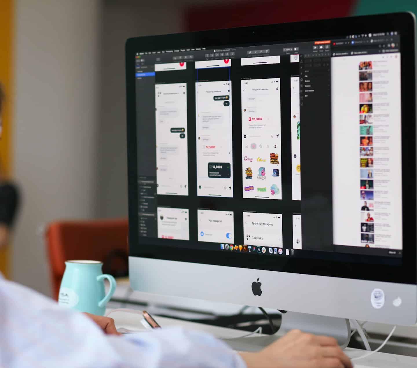 Persona che progetta wireframe di app su un computer desktop con una tazza verde acqua.